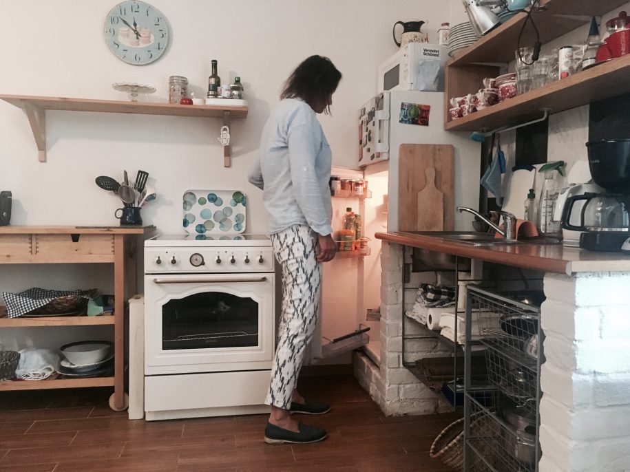 Frau macht Kühlschrank in einer Küche auf