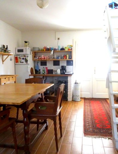 Sonnige Küche mit Esstisch, Küchenzeile und Stufen, die in den 1. Stock führen